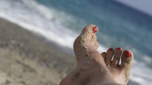 A person's feet covered in sand on the beach