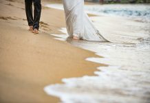 Florida Beach Weddings: Let’s Talk Sand, Scenery & Wildlife man in white dress shirt and blue denim jeans walking on beach during daytime
